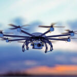 a drone flying in a cloudy sky where the sun goes down